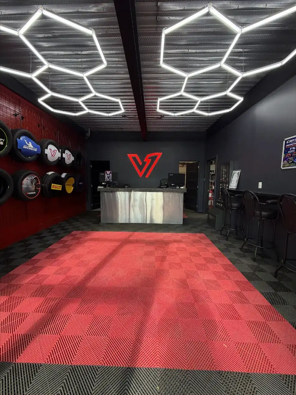 Accueil du garage V1 Pneus + Mécanique à St-Léonard : plafond hexagonal éclairé, logo V1 au mur